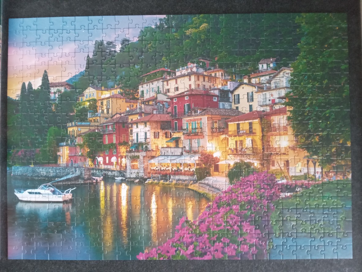 A scenic view of a hillside town on Lake Como at dusk with a boat on the water.