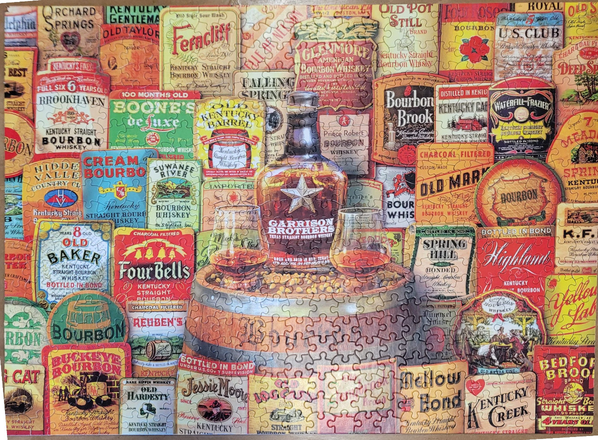 A collage of vintage bourbon labels surrounding a bottle and two glasses of whiskey on a wooden barrel.