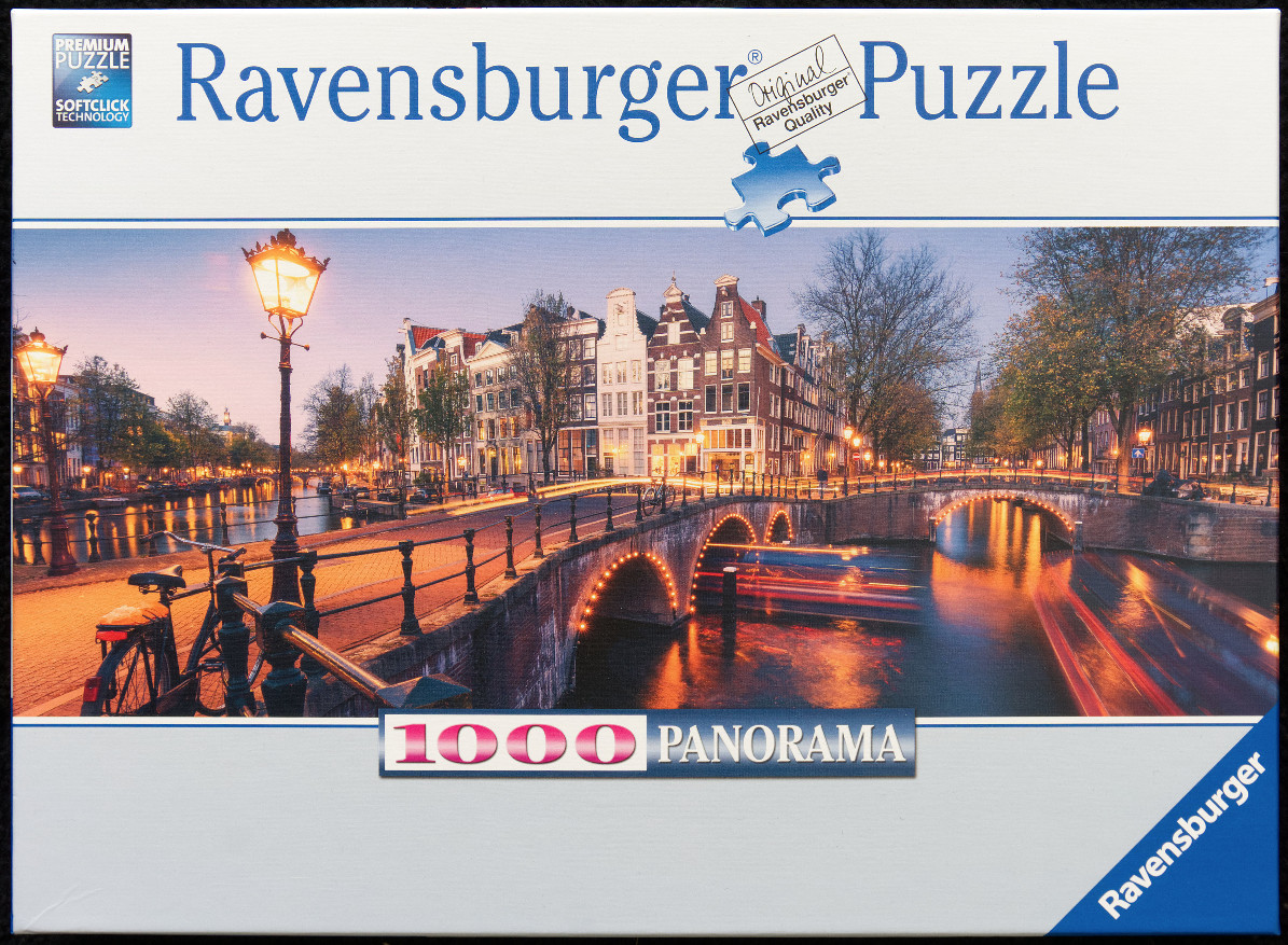 A panoramic view of an Amsterdam canal at twilight with glowing streetlights and historic buildings.