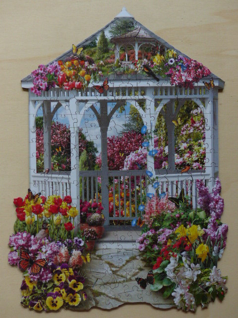 A shaped image of a white gazebo overflowing with colorful spring flowers and butterflies.