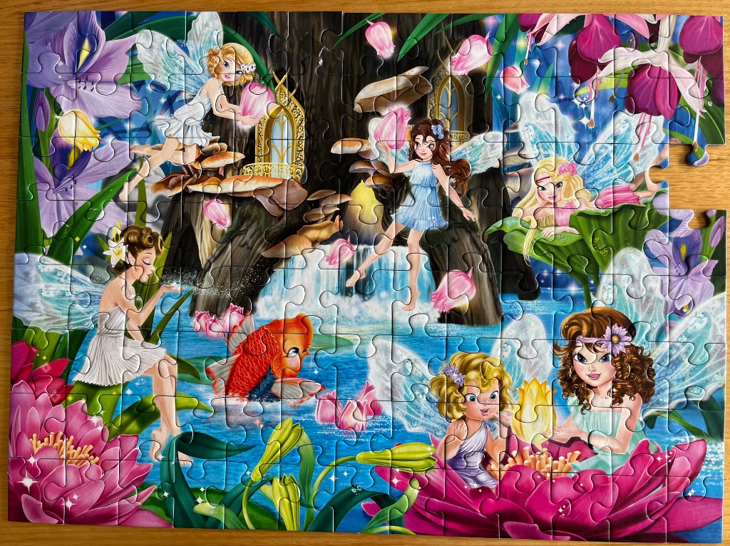 A whimsical illustration of several fairies in a magical garden setting with water and oversized flowers.