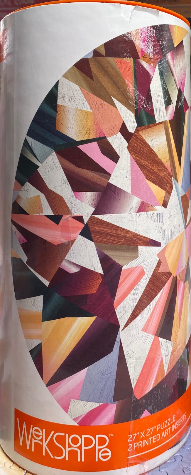 Abstract geometric illustration of a diamond or gemstone in shades of pink, orange, purple, and wood grain textures.