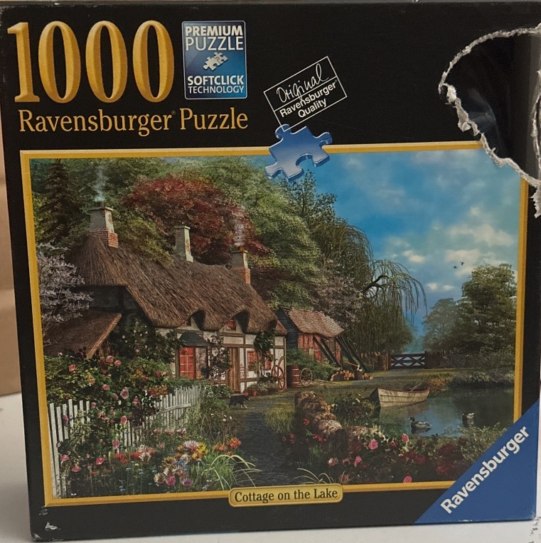 An idyllic thatched-roof cottage nestled by a lake, surrounded by a lush garden and trees.