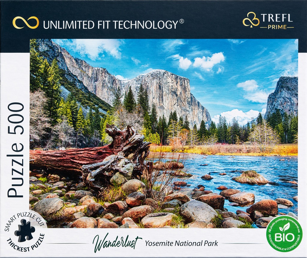 Scenic view of a river, rocky bank, and large fallen tree with granite mountain peaks in Yosemite National Park.