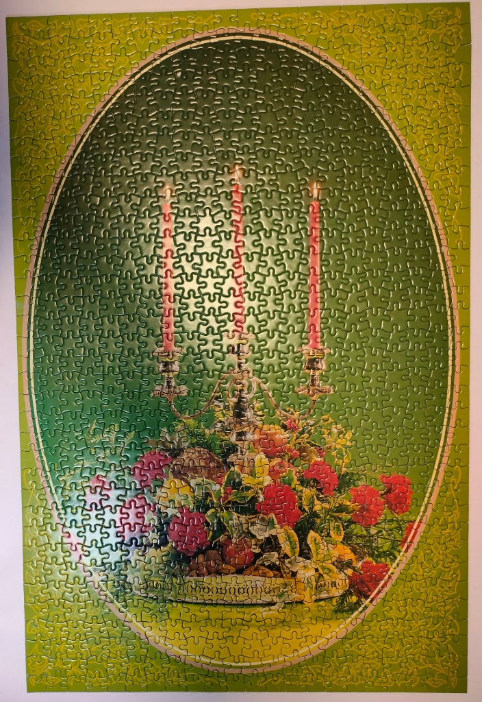An oval-framed illustration of a silver candelabra with three pink candles surrounded by red and pink flowers.