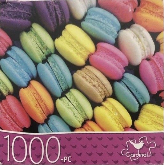 A close-up, top-down view of a vibrant assortment of colorful French macarons arranged in a tight pattern.