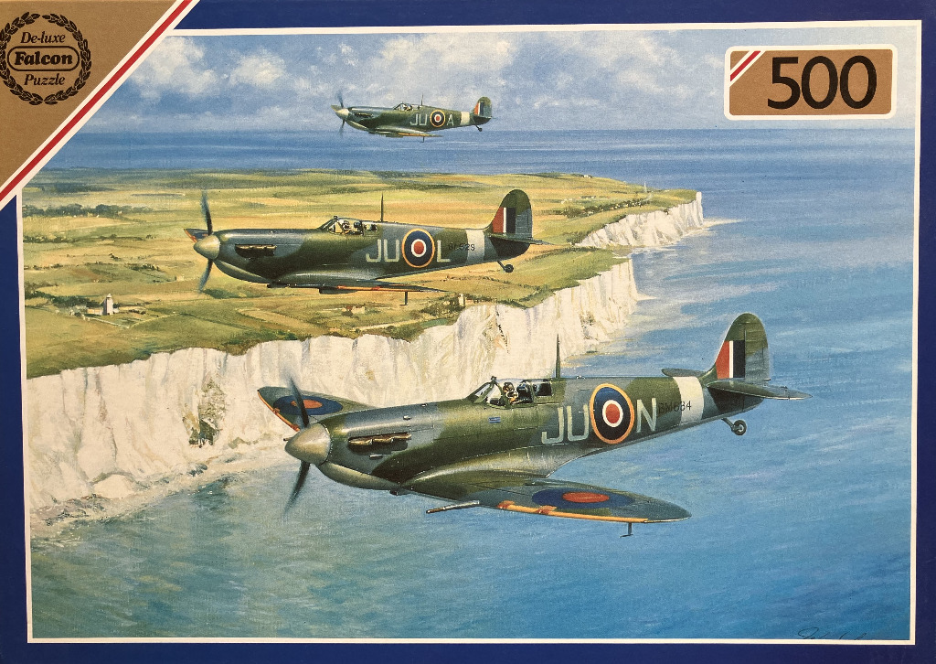 Three Spitfire fighter planes flying in formation over the white cliffs of Dover.