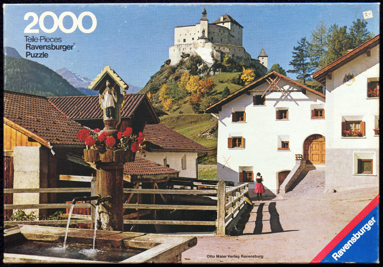 Scenic Austrian village with a wooden fountain, white buildings, and a castle perched on a hill in the background.