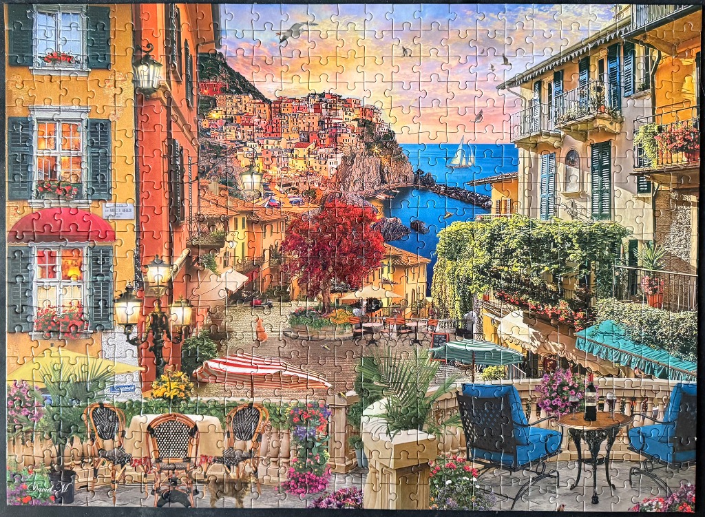 A sunny seaside Italian village with terrace dining and vibrant flowers at sunset.