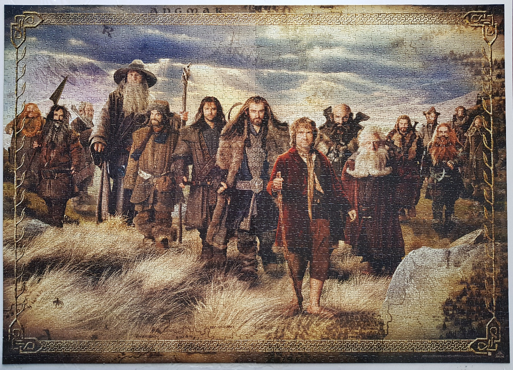 A cinematic group portrait of Bilbo Baggins, Gandalf, and the Company of Dwarves in a field.