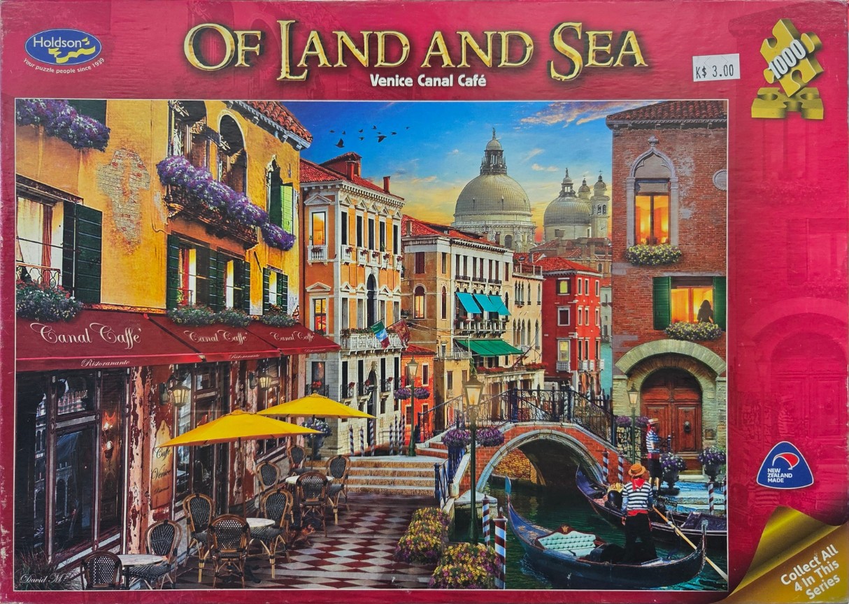 Venetian canal scene with a streetside café, a stone bridge, and gondoliers at sunset.