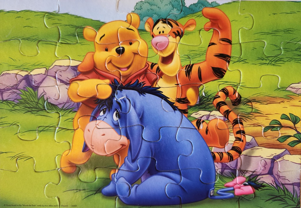 Winnie the Pooh, Tigger, and Eeyore standing together in a grassy meadow.