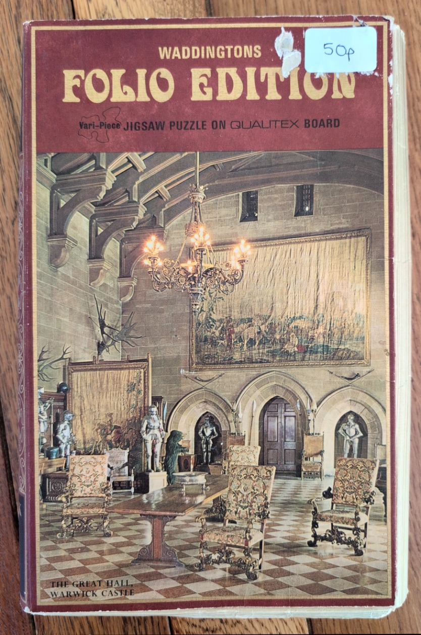 A vintage illustration of the interior of the Great Hall at Warwick Castle with stone walls, suits of armor, and tapestries.