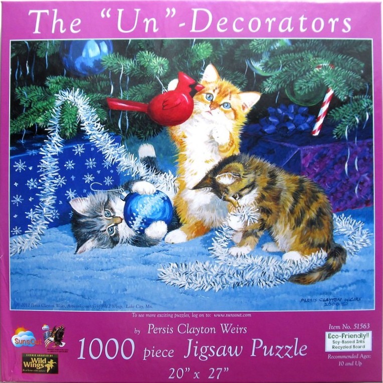 Three kittens playing with Christmas ornaments under a decorated tree