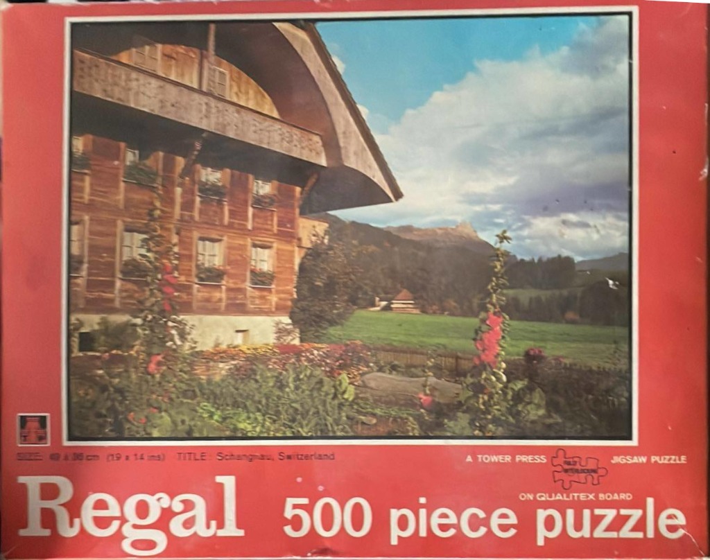 A vintage photograph of a large, wooden Swiss farmhouse in Schangnau with flowers in the foreground.