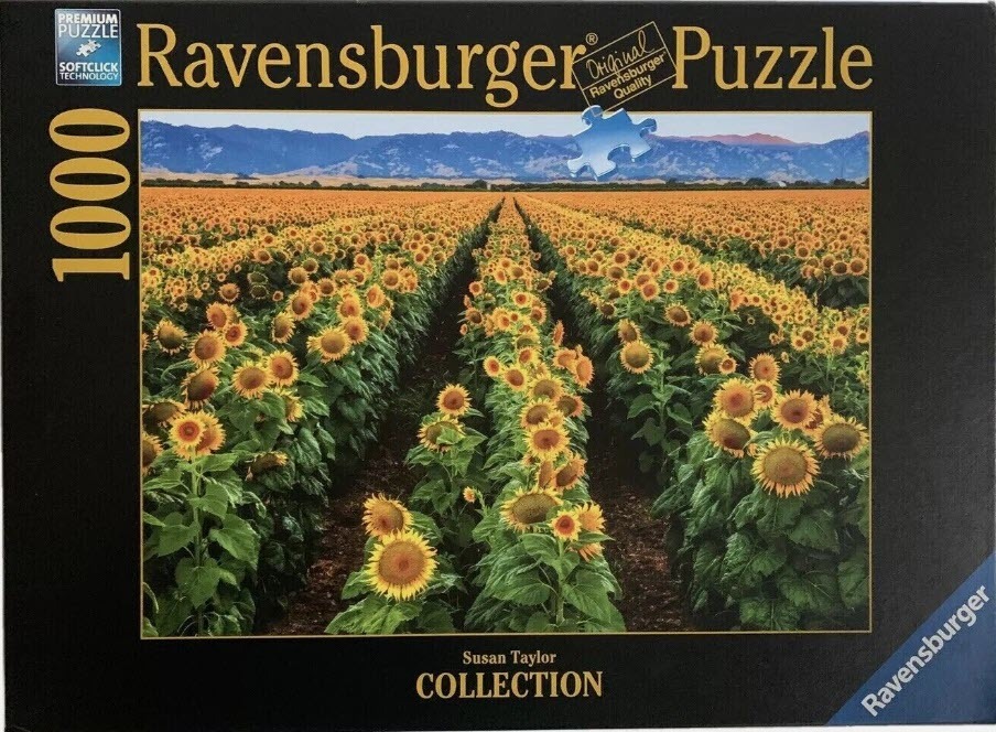 A photograph of rows of sunflowers stretching toward distant blue mountains under a clear sky.