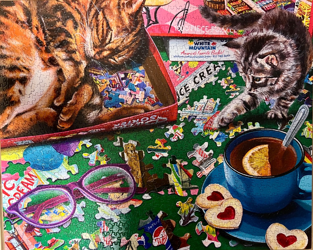 A cozy scene featuring two cats, a blue teacup with a lemon slice, heart-shaped cookies, and purple glasses.