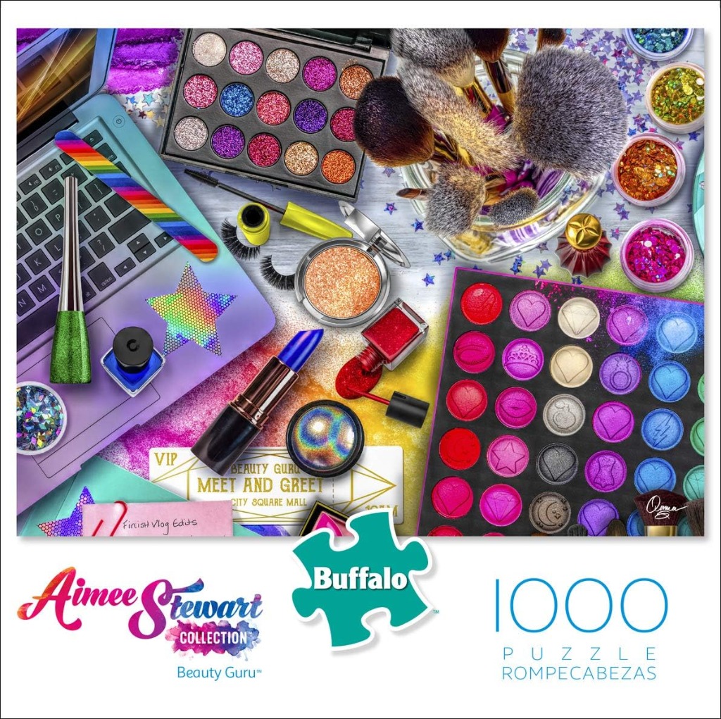 A top-down view of beauty products, makeup palettes, and a laptop on a colorful, glittery surface.