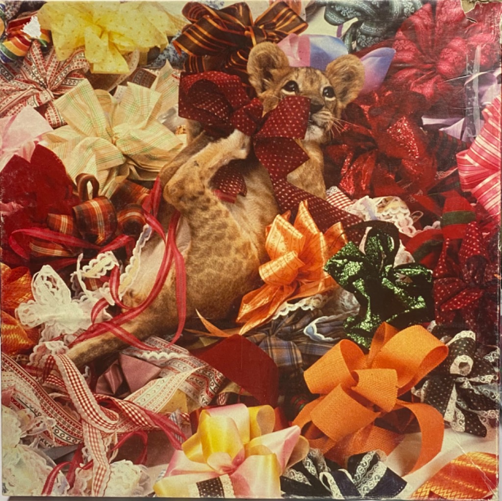A cute lion cub sitting in a pile of various colorful gift bows and ribbons.