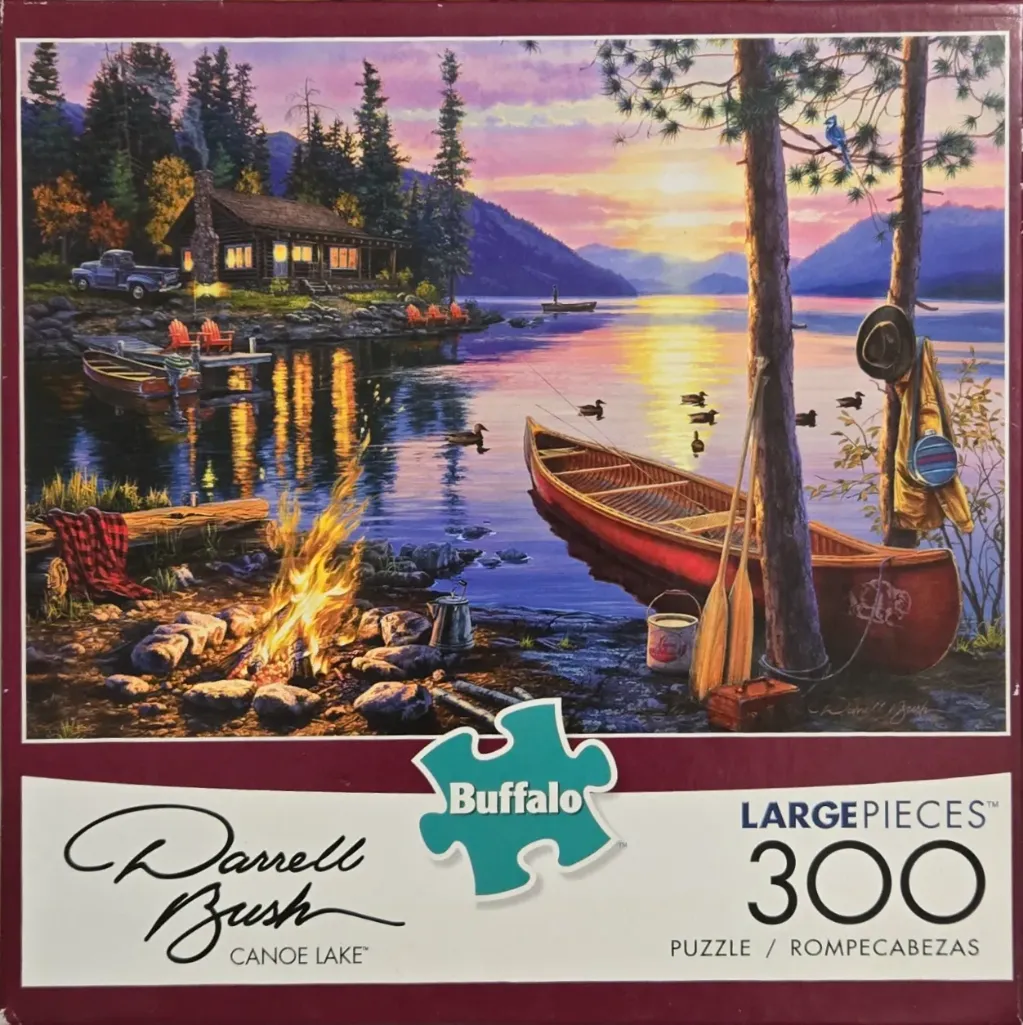 A peaceful lakeside cabin scene at sunset with a campfire and canoe in the foreground.