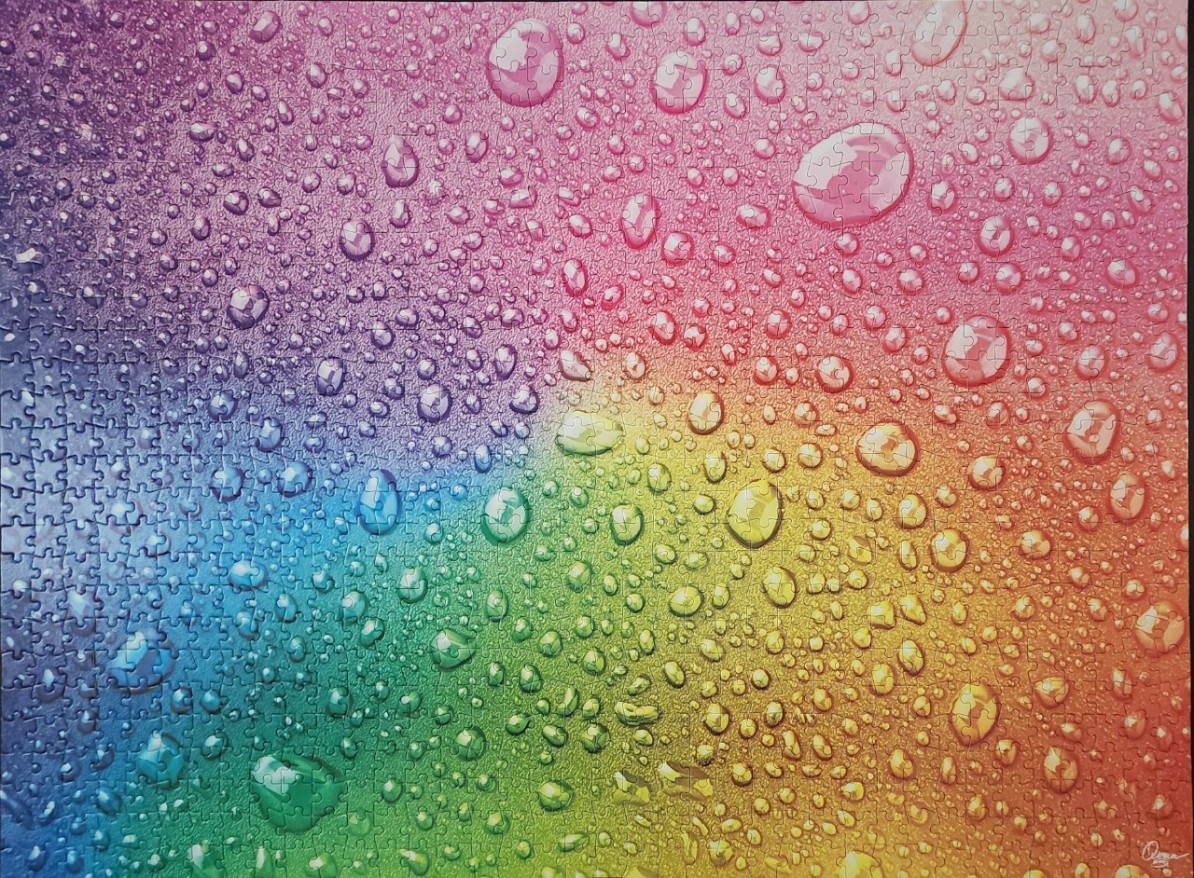 Close-up of a rainbow-colored surface covered in numerous water droplets