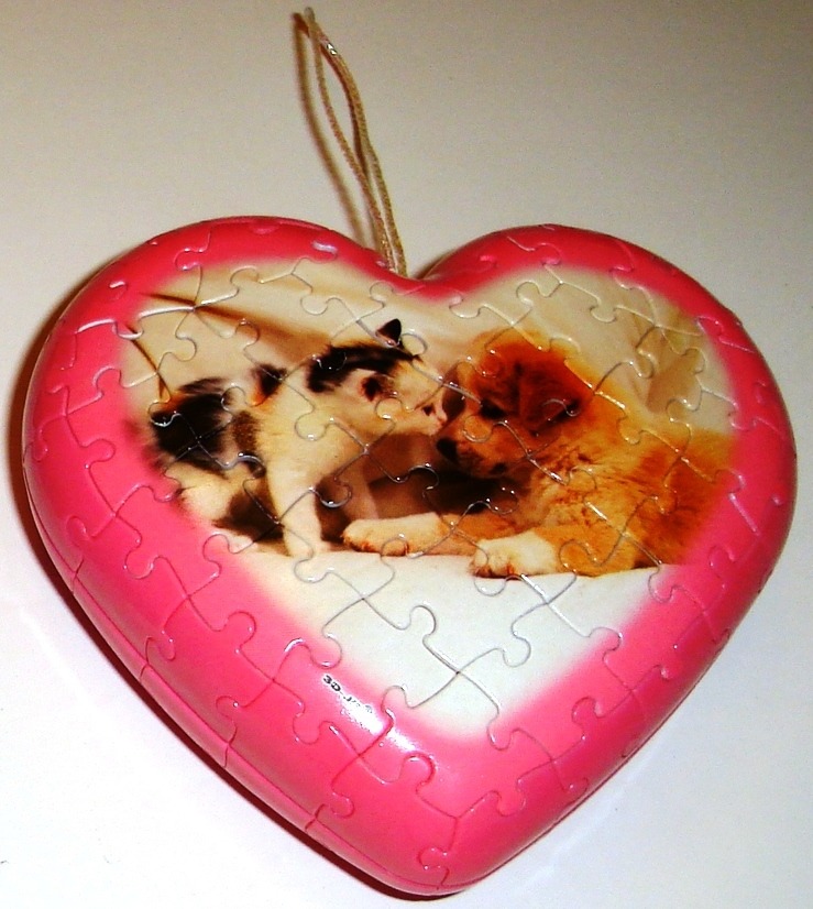 Heart-shaped ornament featuring a photograph of a kitten and a puppy touching noses.
