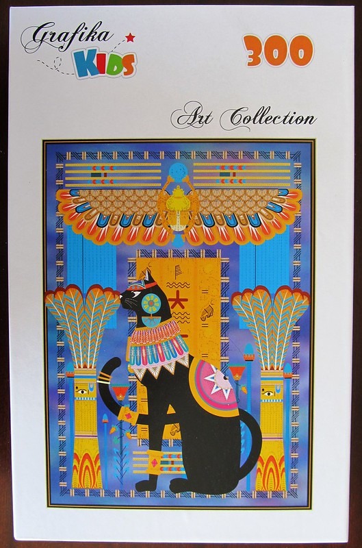 An illustration of an ornate black Egyptian cat adorned with jewels against a backdrop of ancient Egyptian architecture.