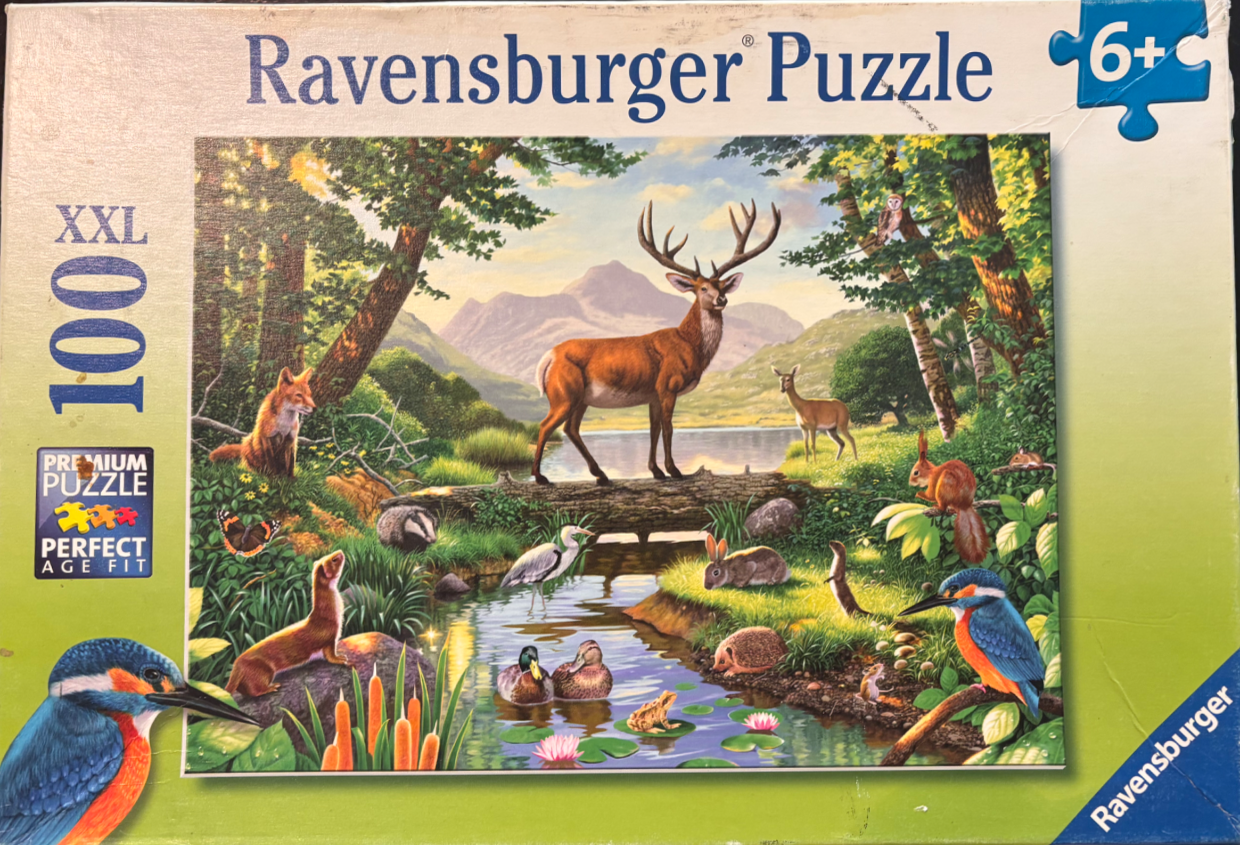 A lush woodland landscape featuring a large stag and various small forest animals by a stream.