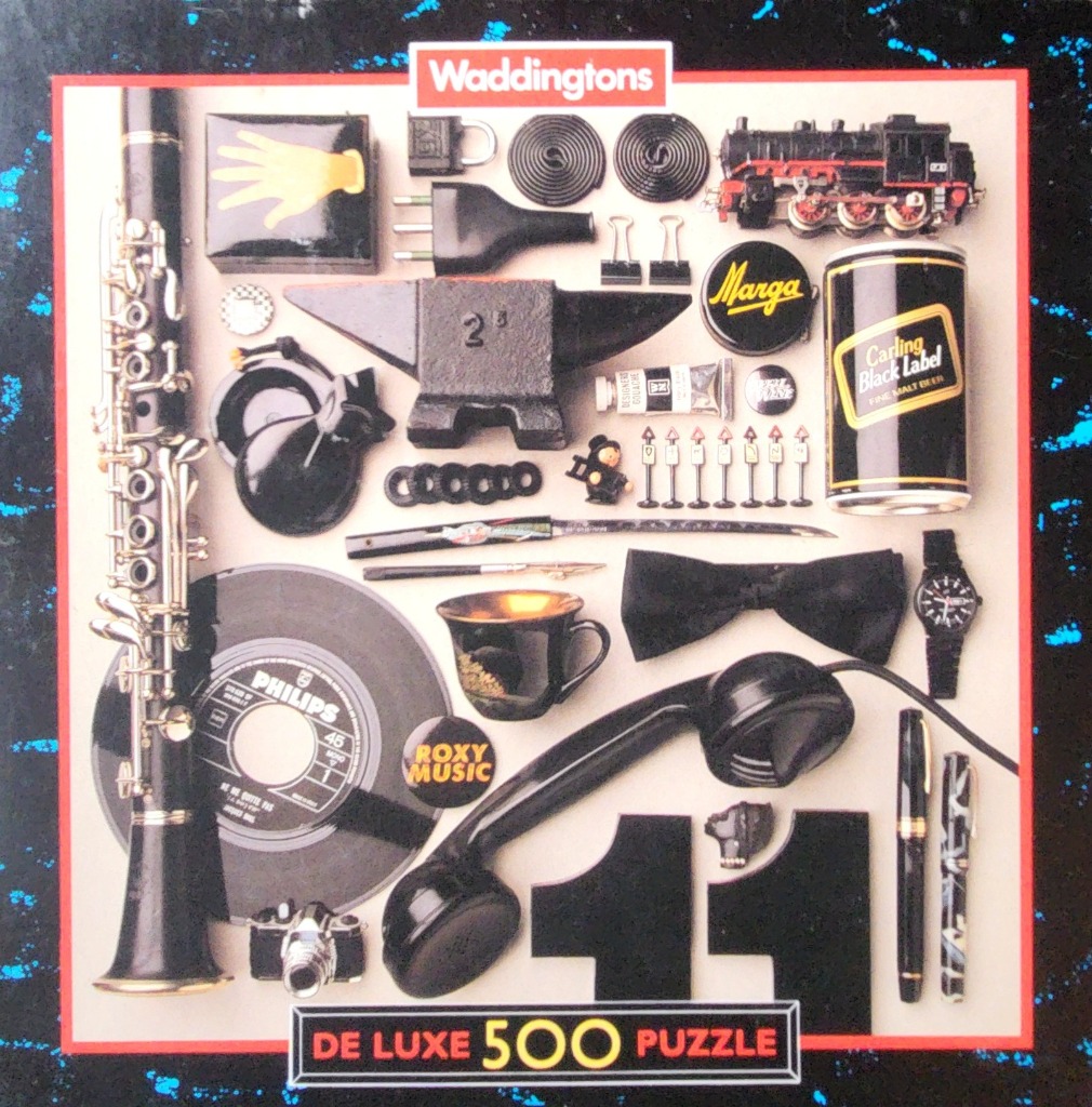 A flat lay composition of various black objects including a clarinet, vinyl record, telephone, and train on a light backgroun