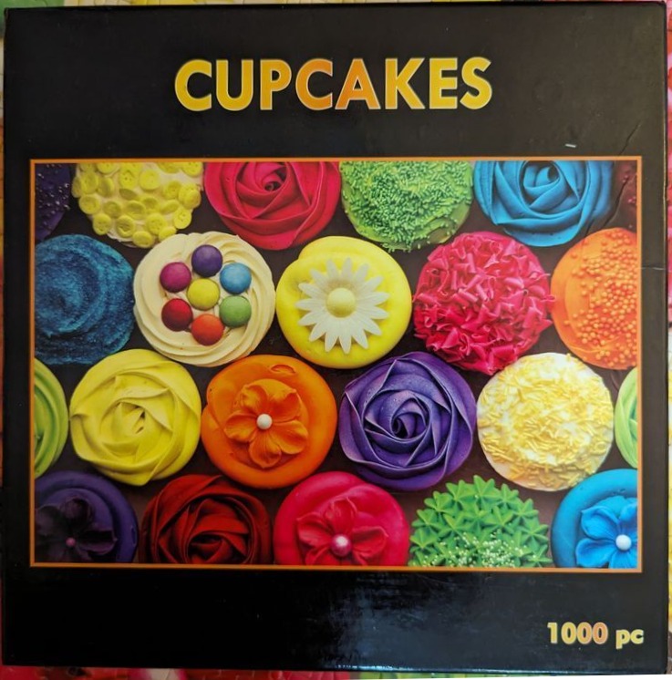 Top-down view of many colorful, elaborately frosted cupcakes arranged in a grid pattern.