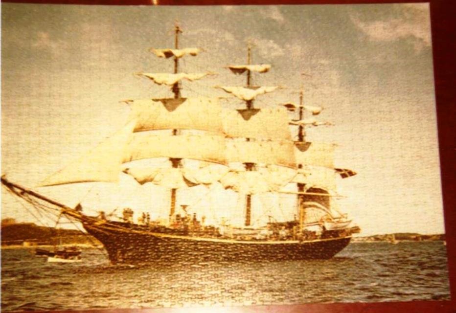 A tall ship with white sails navigating open water in a vintage sepia-toned style.