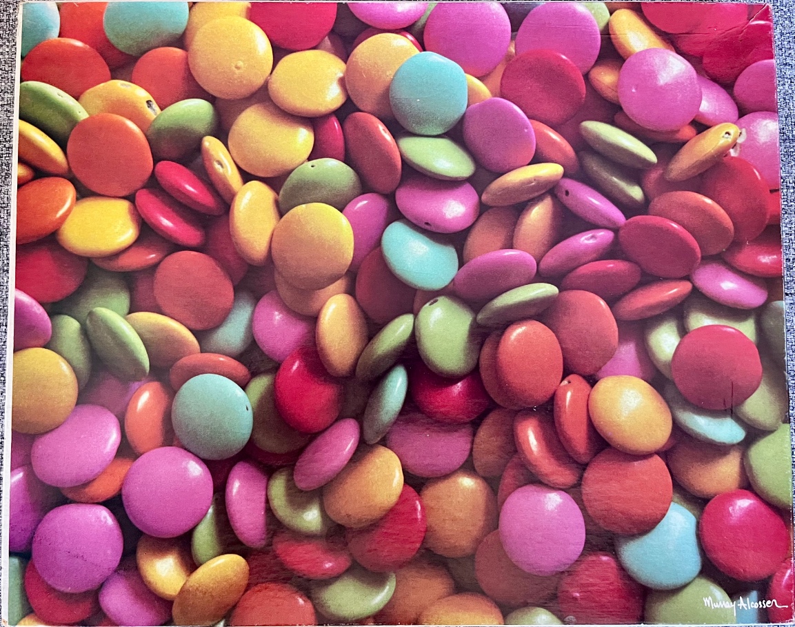 A dense, top-down view of a pile of colorful, round, candy-coated chocolate disks.