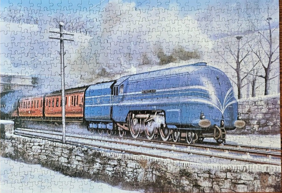A blue Princess Alice streamliner steam locomotive pulling passenger cars through a wintry landscape.