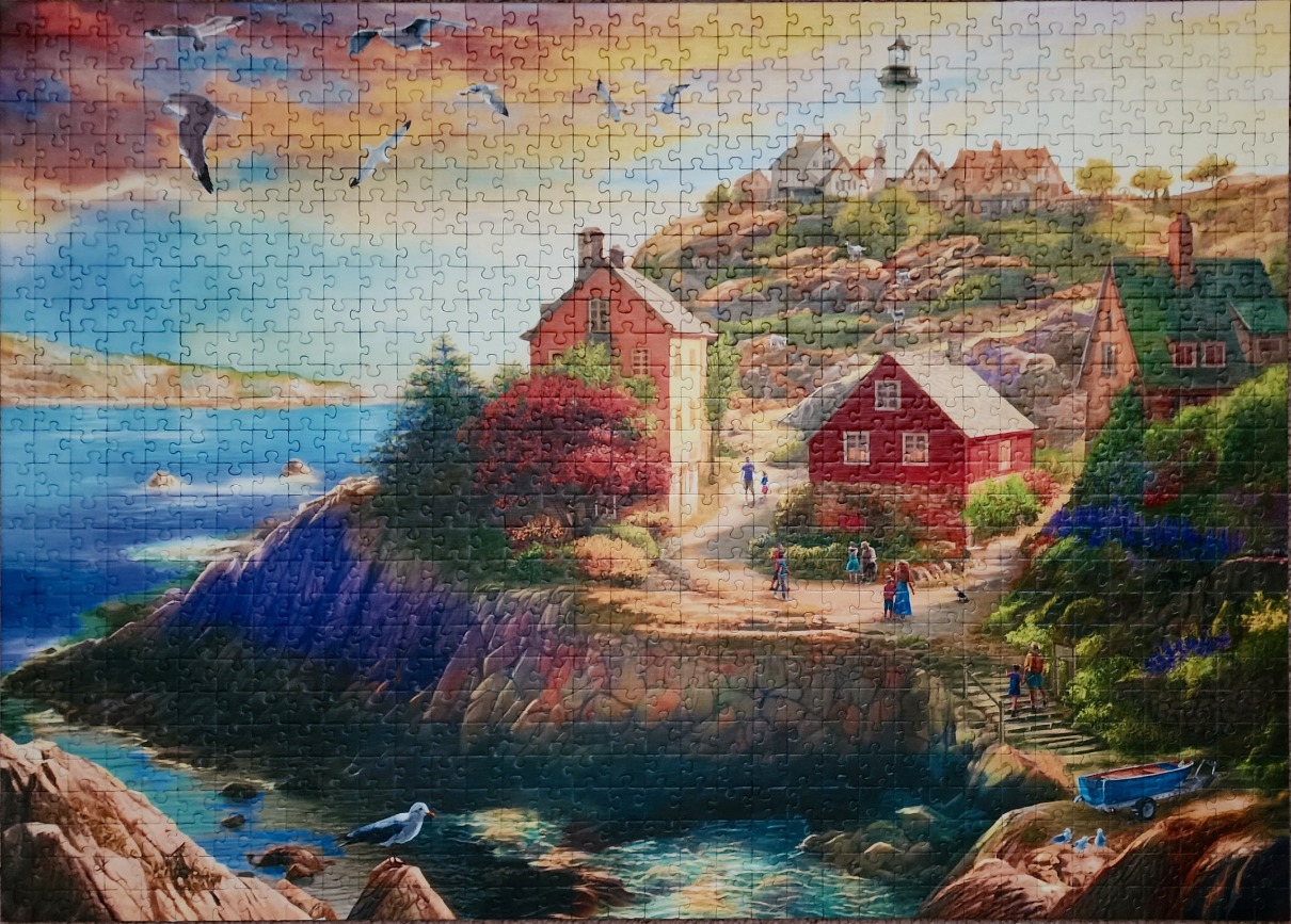 A coastal village scene with houses on a rocky cliff under a dramatic sunset sky.