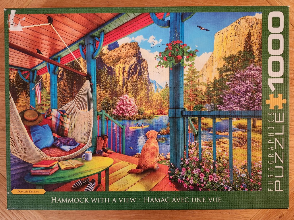 A golden retriever looks out from a porch with a hammock toward a mountain lake scene.