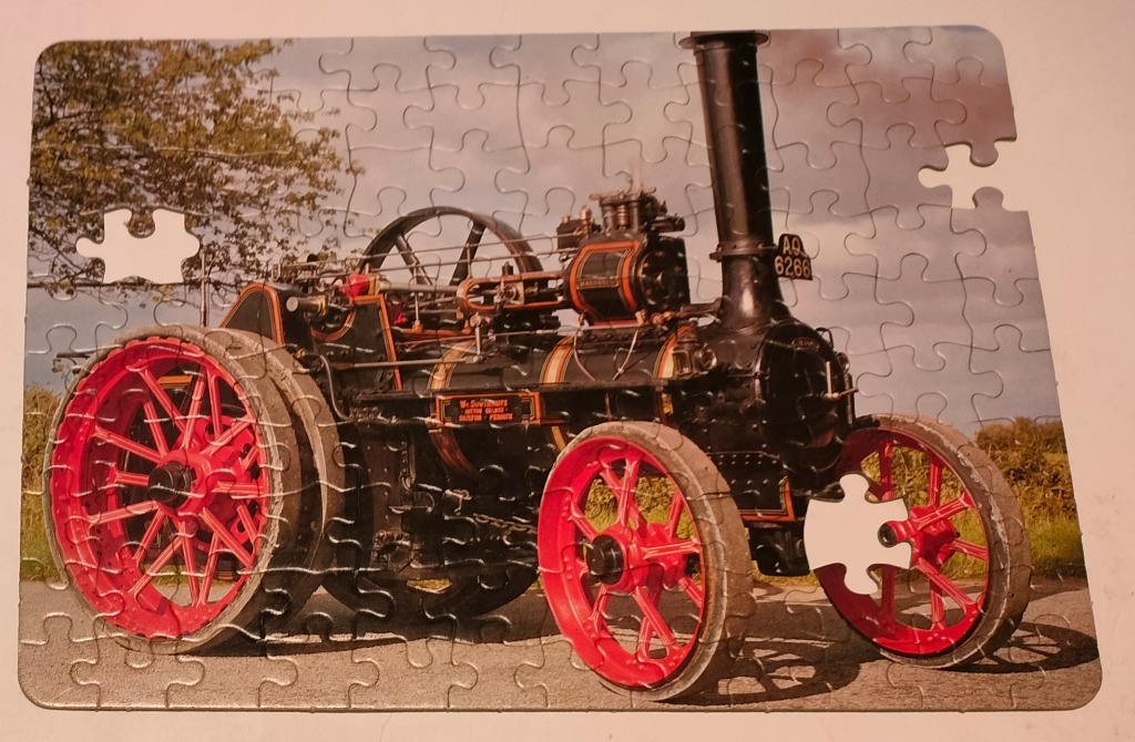 Vintage steam traction engine in red and black on a country road