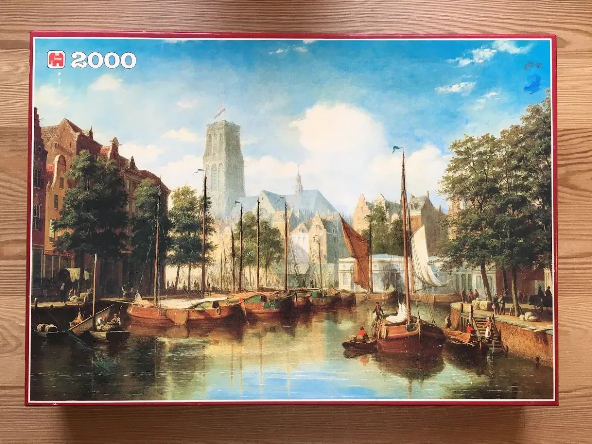An oil painting of a 17th-century Dutch harbor scene with sailing boats, canals, and a large cathedral tower.