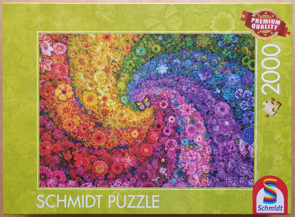 A vibrant spiral of thousands of colorful flowers, transitioning from warm yellow and orange to cool purple and blue.