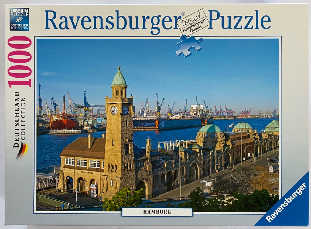 Scenic photograph of the Hamburg Landungsbrücken harbor piers with a tall clock tower against a clear blue sky.