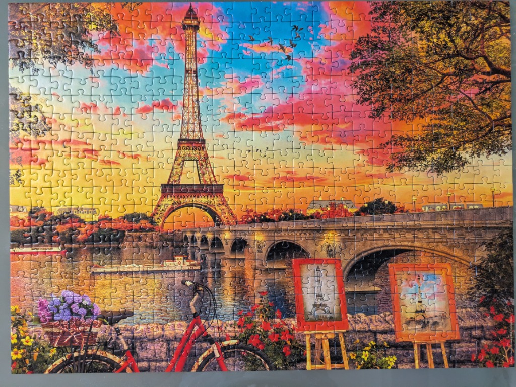 The Eiffel Tower at sunset with a red bicycle and easels in the foreground.