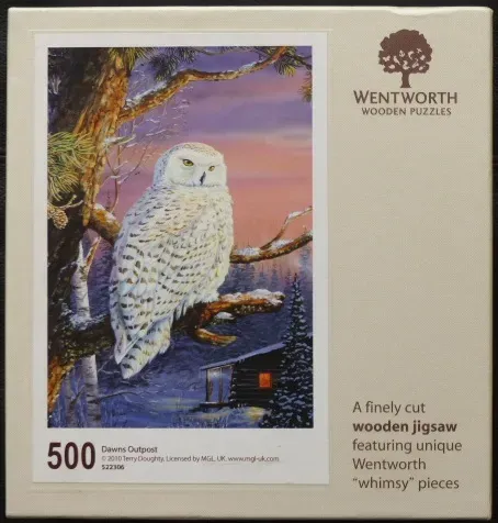 A snowy owl perched on a pine branch above a cabin in a winter landscape at dawn.