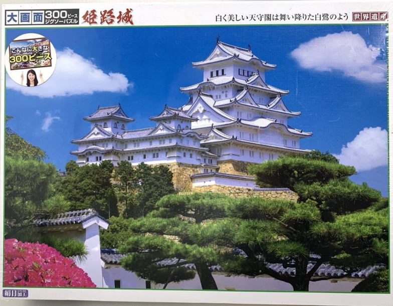 Himeji Castle with white towers against a vibrant blue sky and lush green trees.