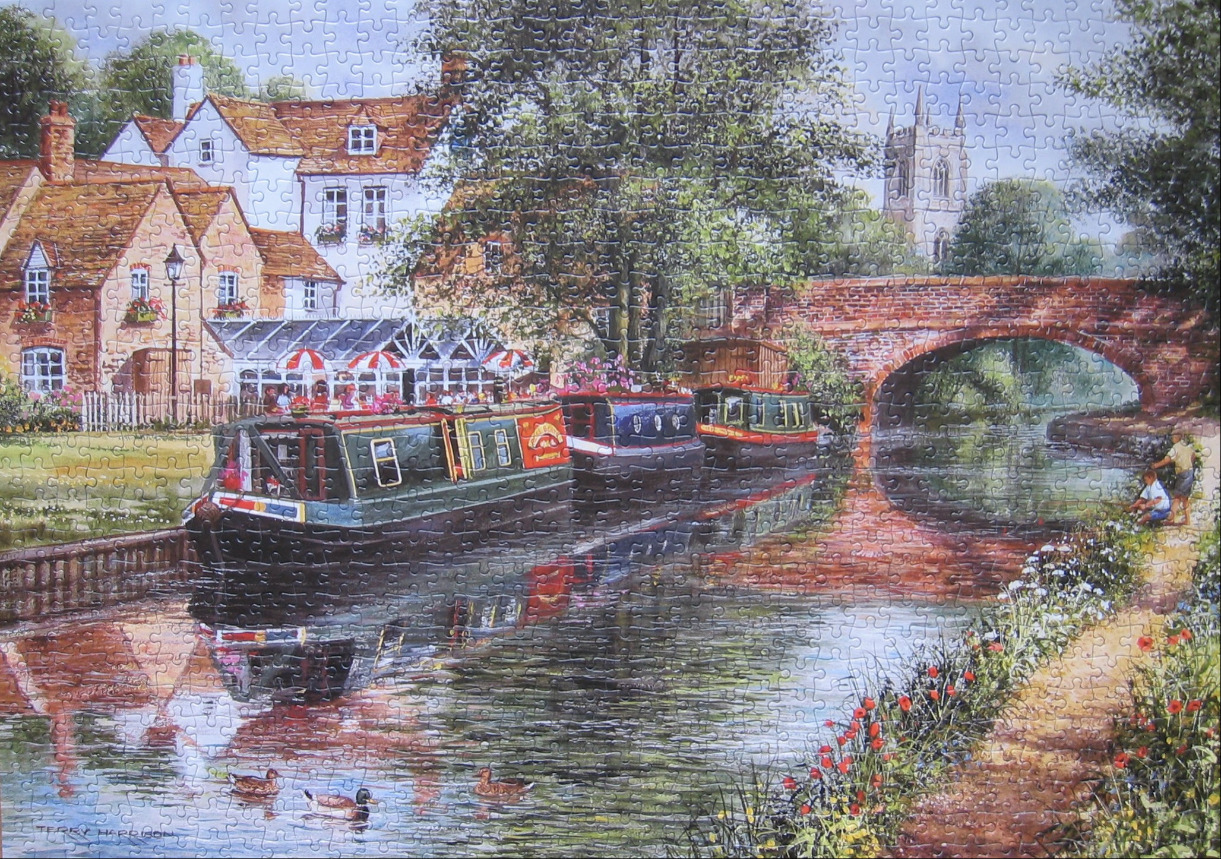 A scenic English canal side village with narrowboats, a stone bridge, and a pub.