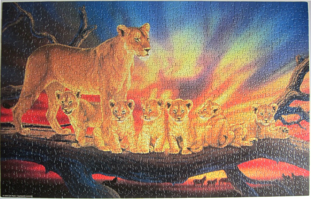 A lioness and five cubs perched on a large tree branch against a vibrant, fiery sunset background.