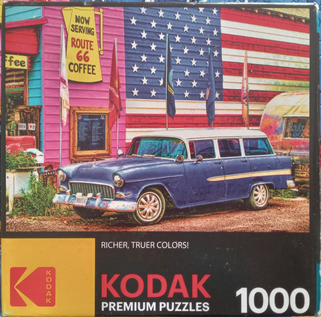 A vintage blue station wagon parked in front of a building painted with an American flag mural.