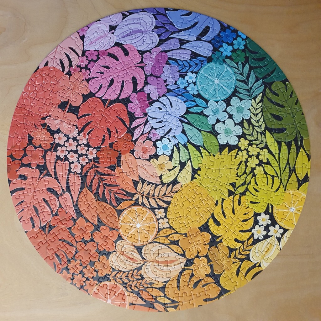 Circular illustration of tropical plants, fruits, and flowers arranged in a vibrant rainbow color gradient.