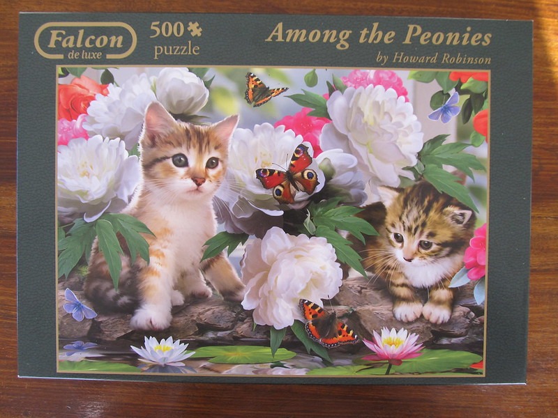 Two kittens sitting among large white peony flowers and butterflies.