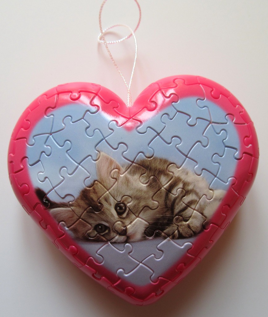 A heart-shaped ornament featuring a photograph of a fluffy tabby kitten.