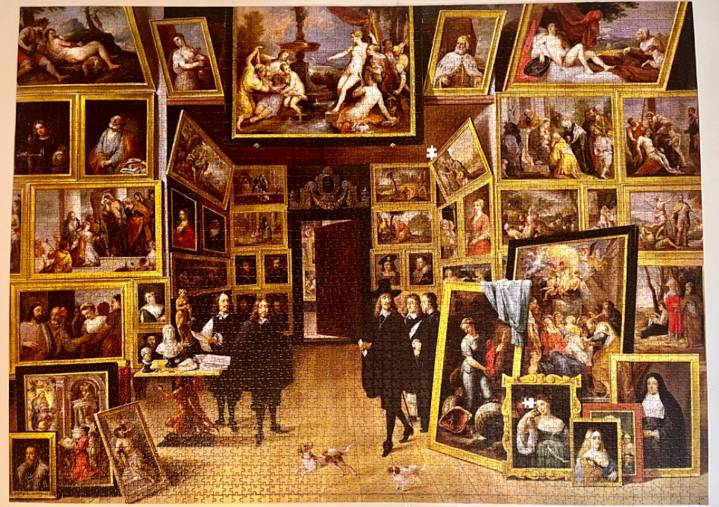 A Renaissance-style gallery filled with numerous paintings covering the walls and floor, with people and dogs present.