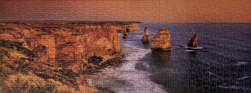 Panoramic view of the Twelve Apostles limestone stacks along a rugged Australian coastline at sunset.